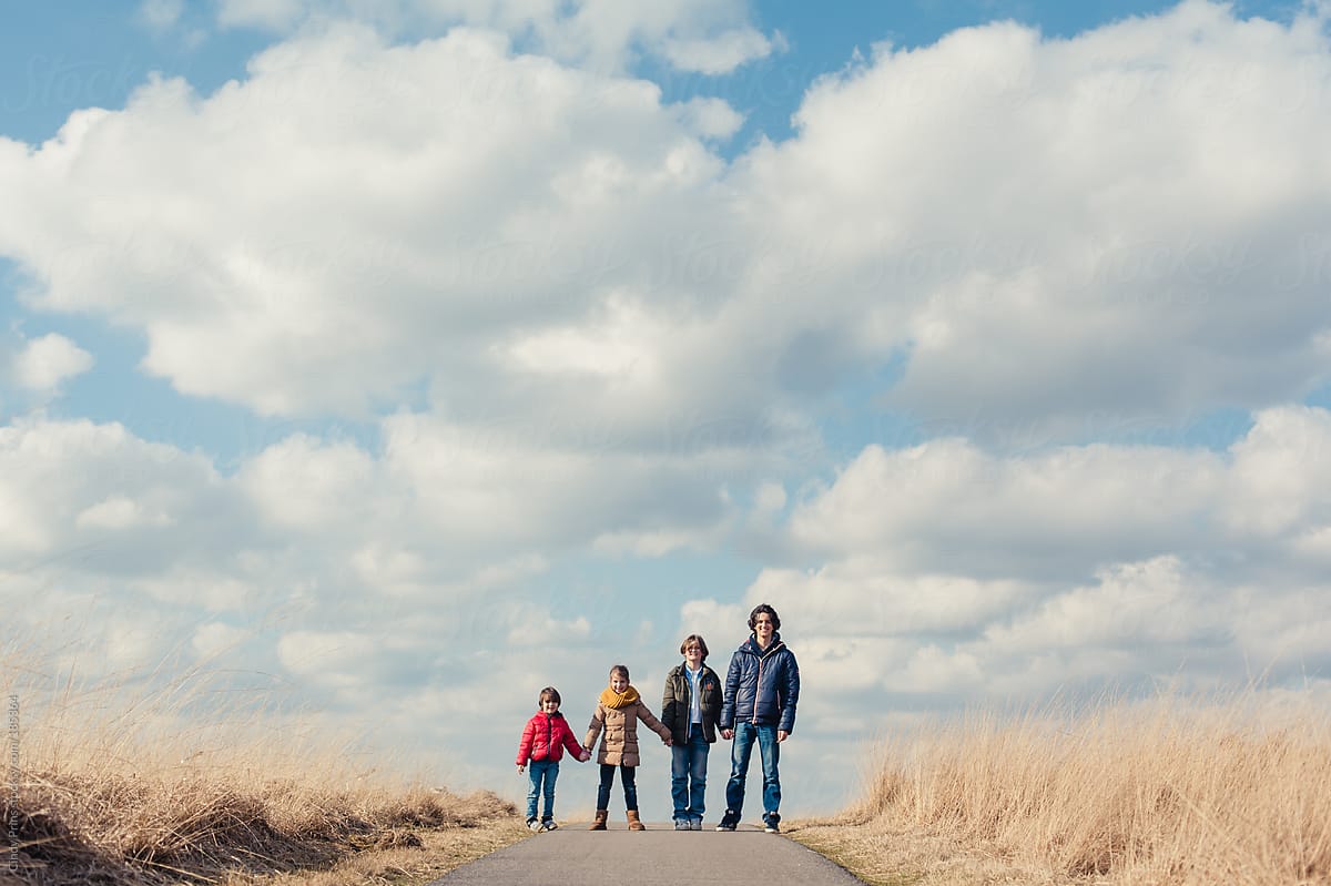 Four kids in different ages holding hands under a big sky