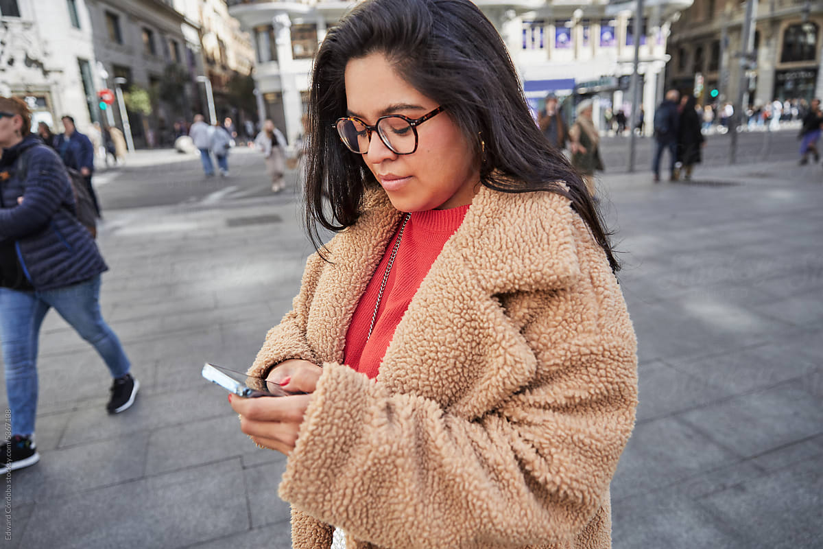 Young Latin Woman Texting In The Middle of  City Center