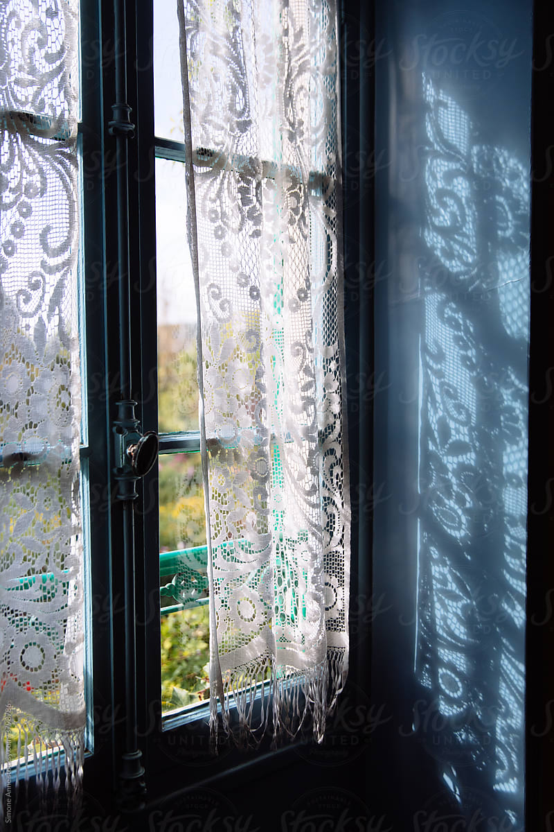 A blue window with a lace curtain