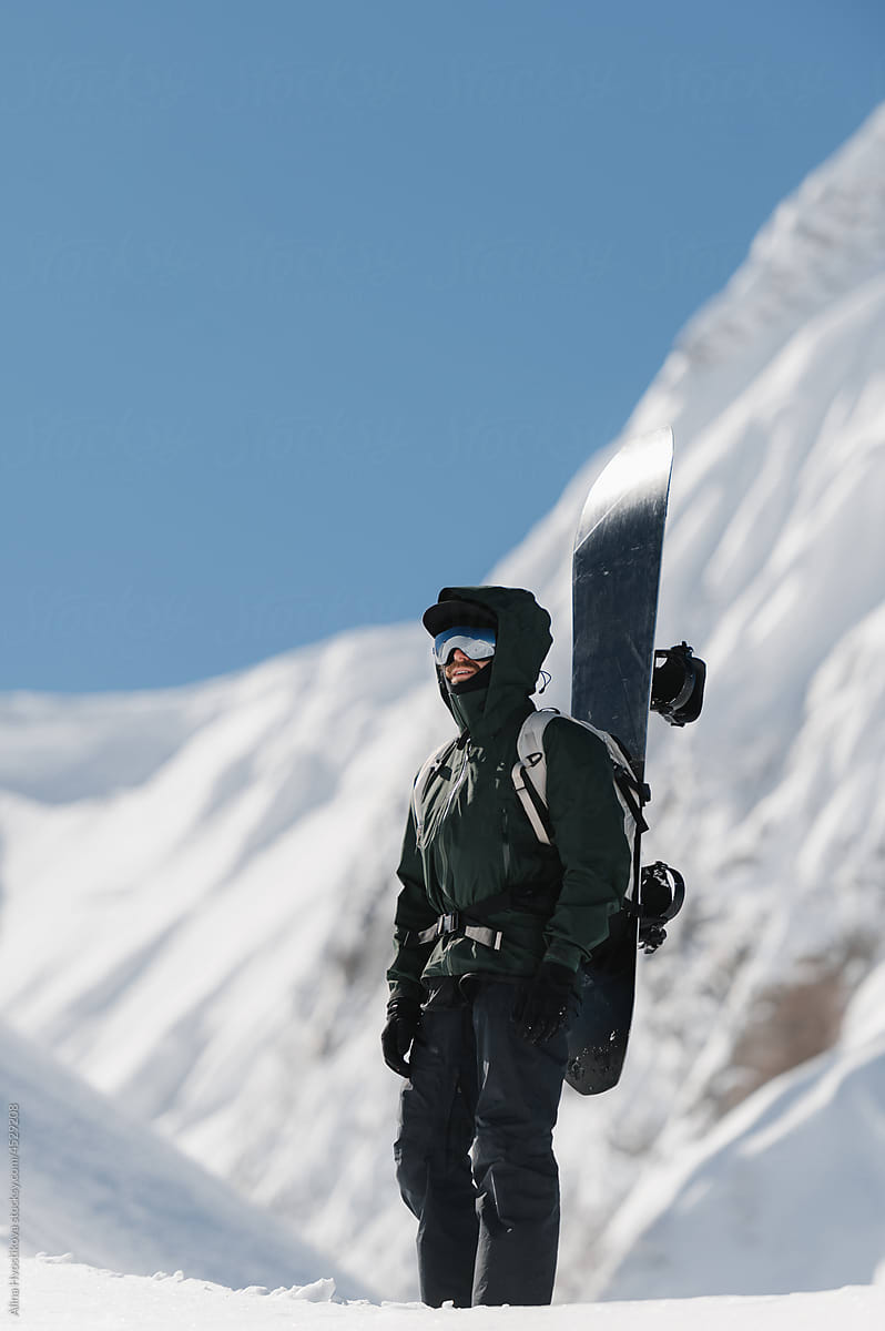 Male snowboarded against snowy mountains