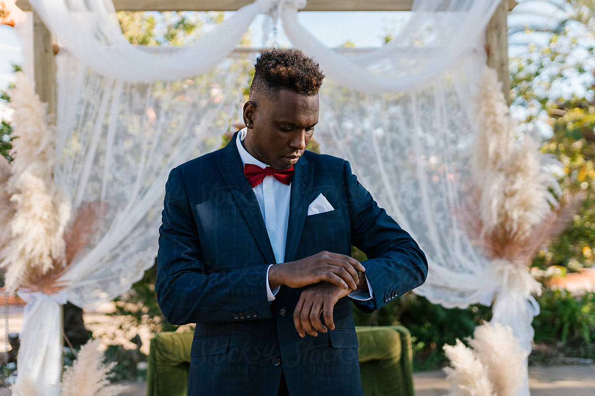 Black man in suit checking time