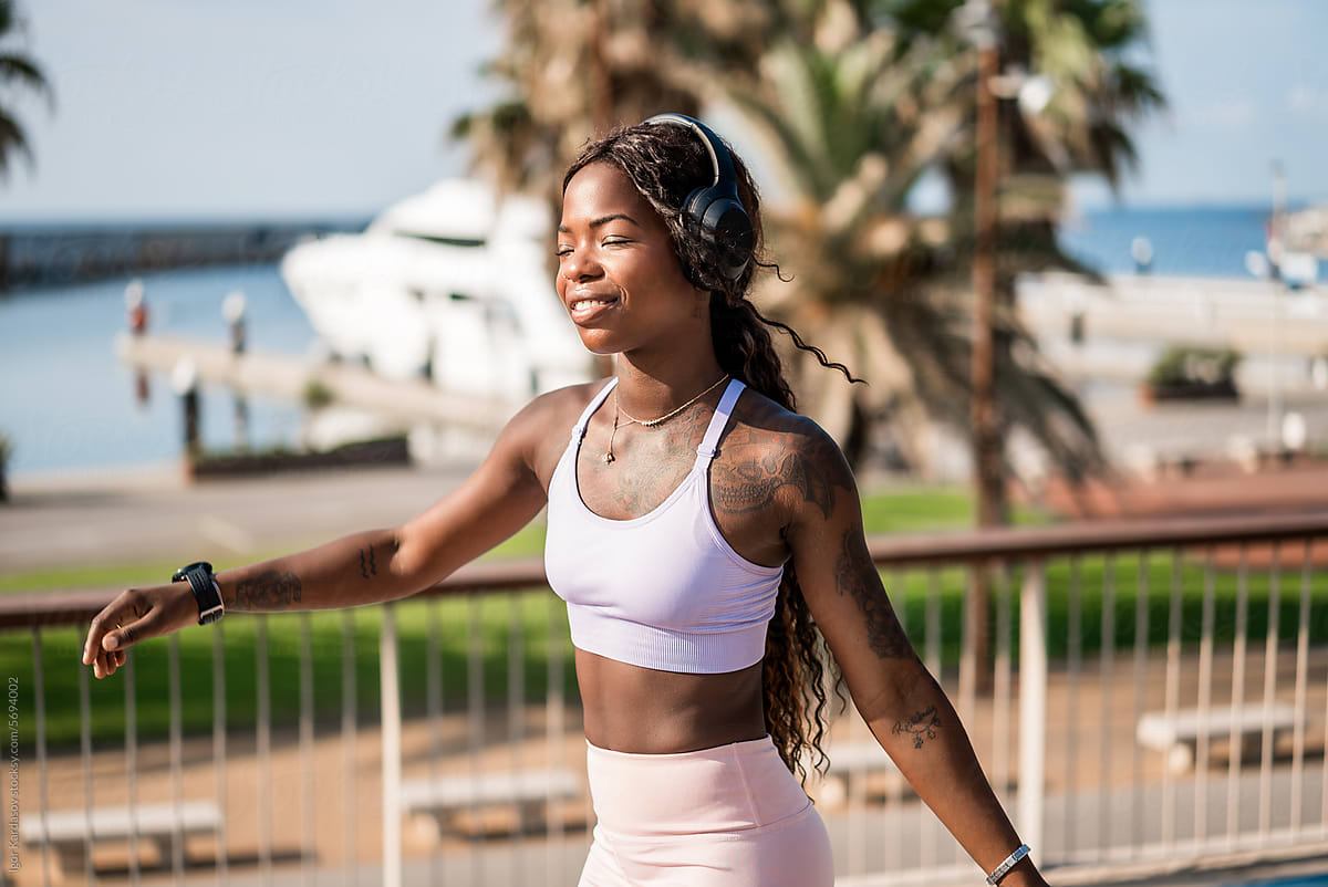 Happy young black woman with headphones walking in day