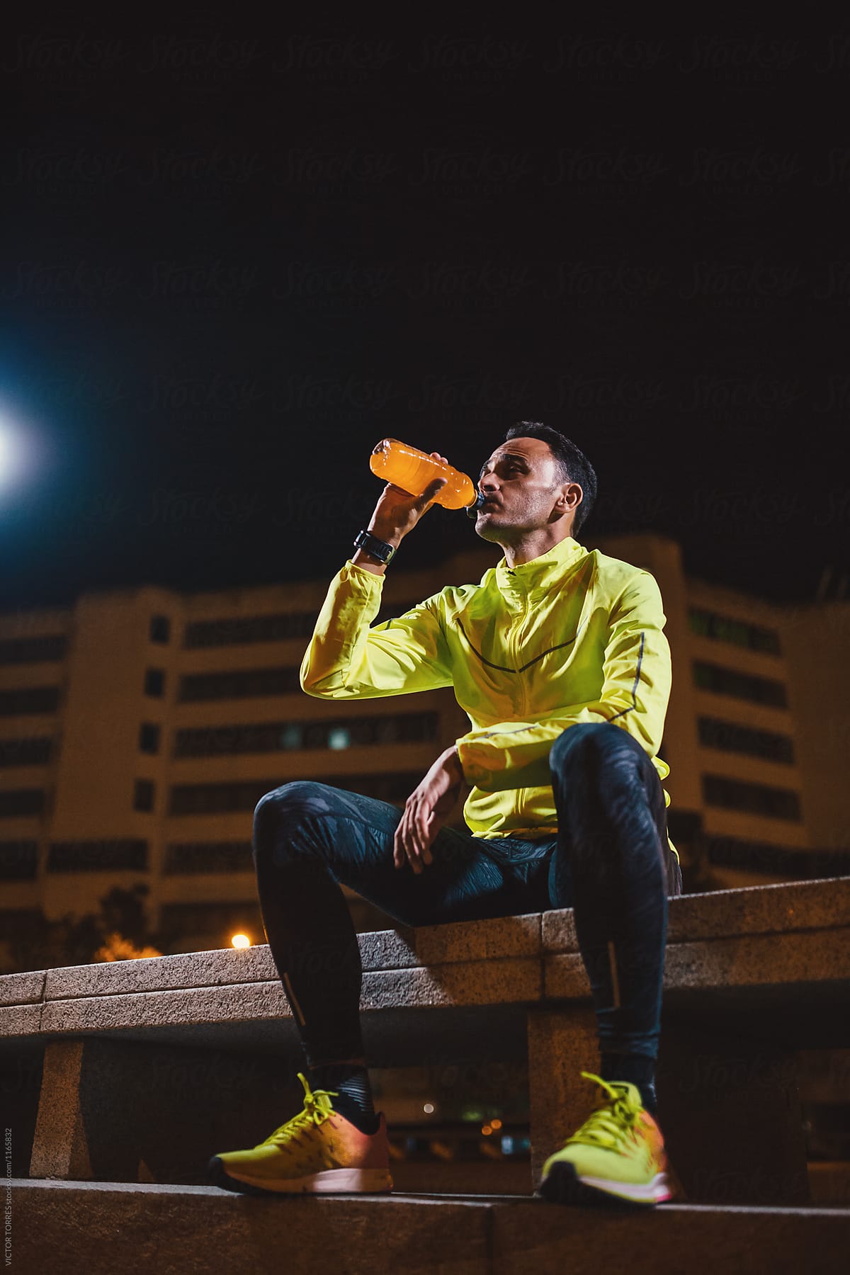 Sportsman drinking orange drink from bottle