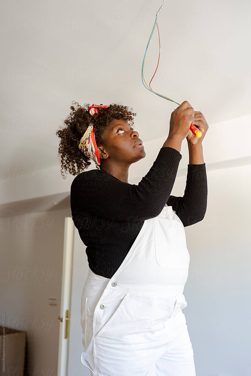 Pregnant woman fixing electric installation in new home