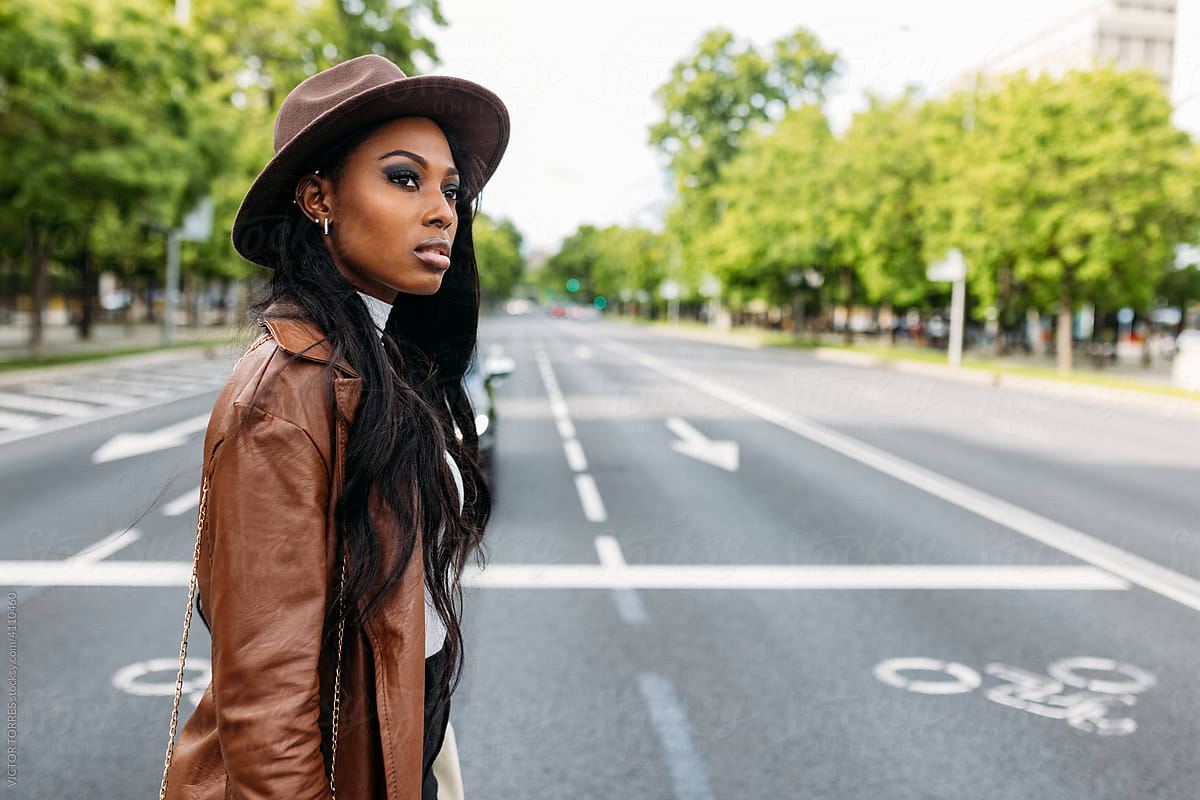 Serious black woman in leather coat and hat