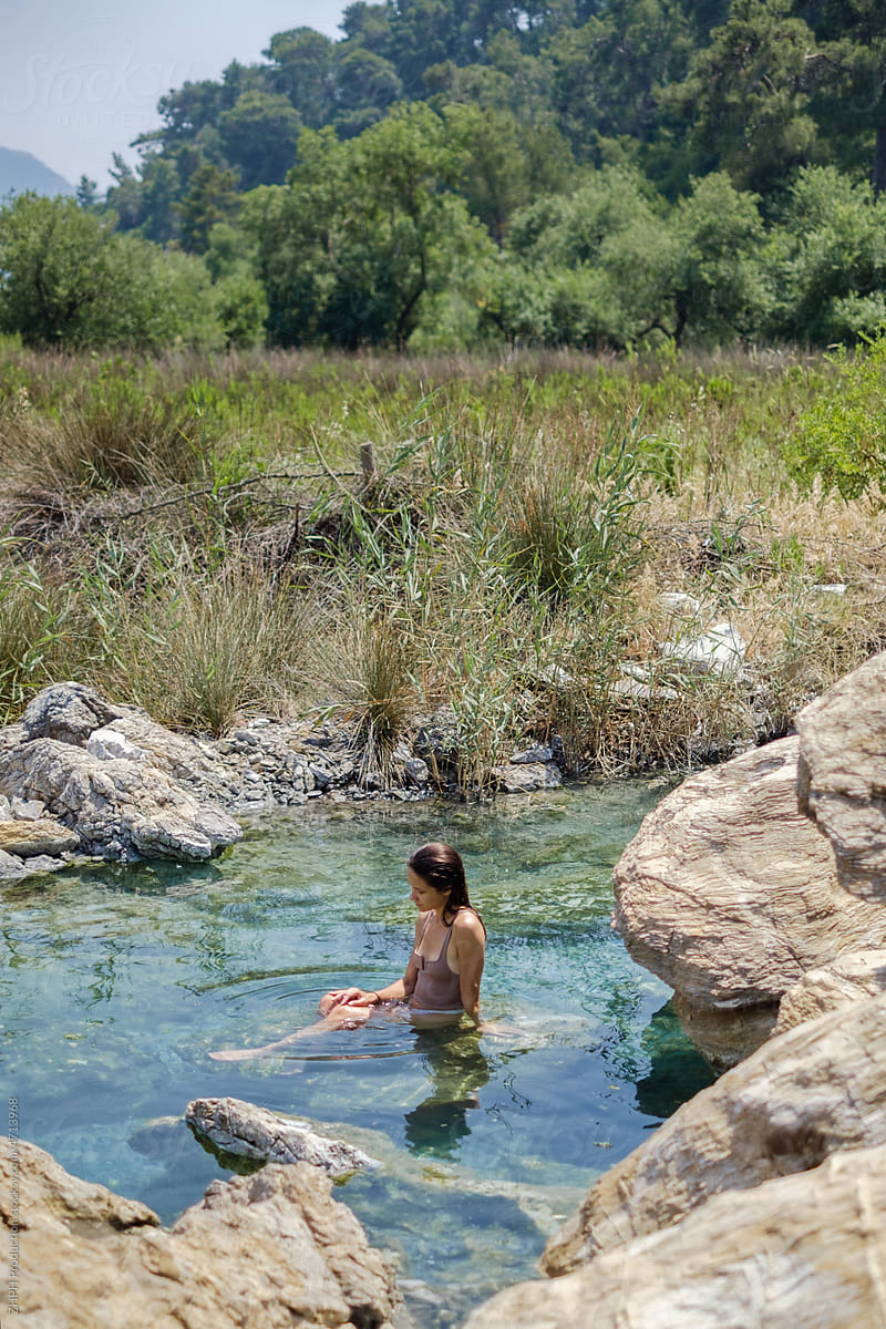 Young woman relaxing in natural spring pond