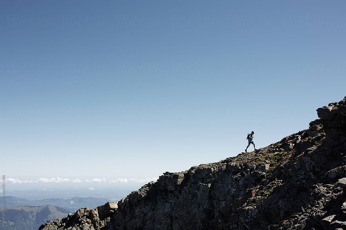 Silhouette of a hiker on a mountain ridge in a sunny day