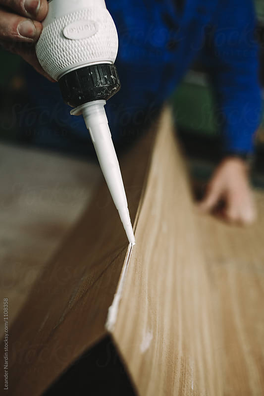detail of a woodworker applying some glue into the veneer