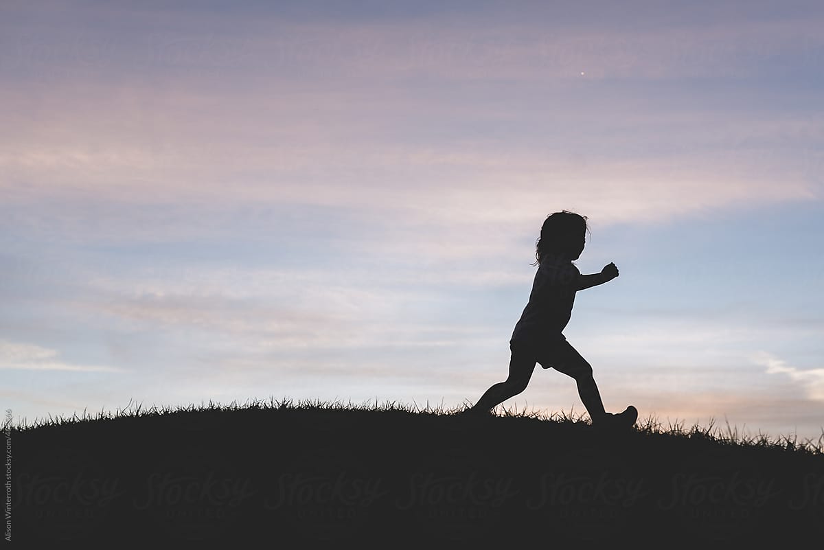 Little Girl Silhouette Running On A Hill At Sunset