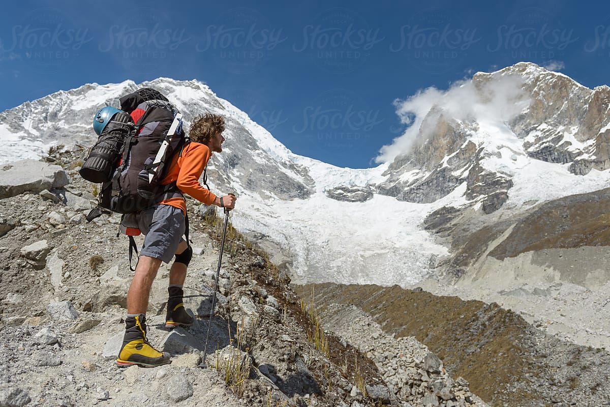 Hiker with heavy backpack looking at the mountain
