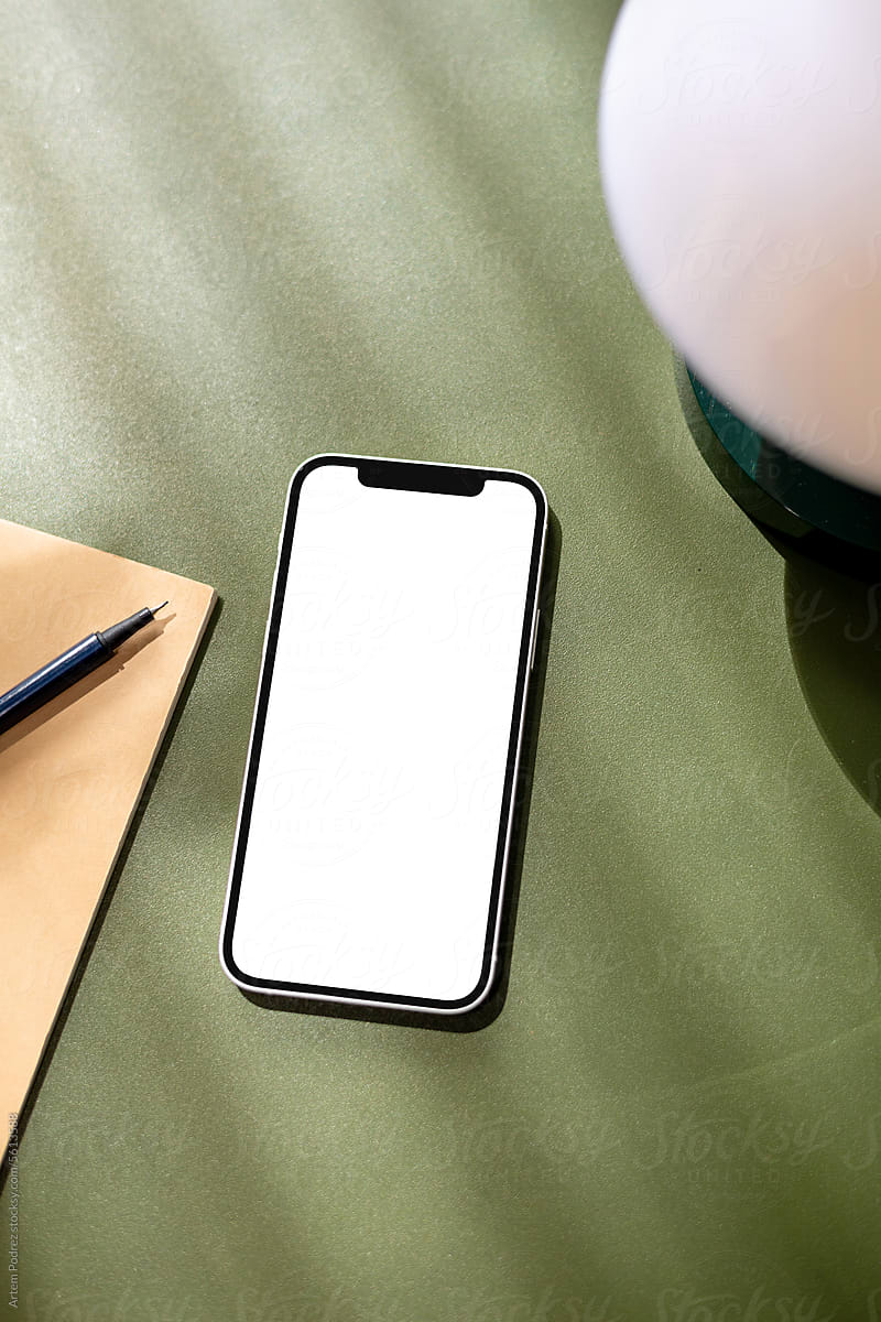 A mock-up of a mobile phone with a white screen on a green table