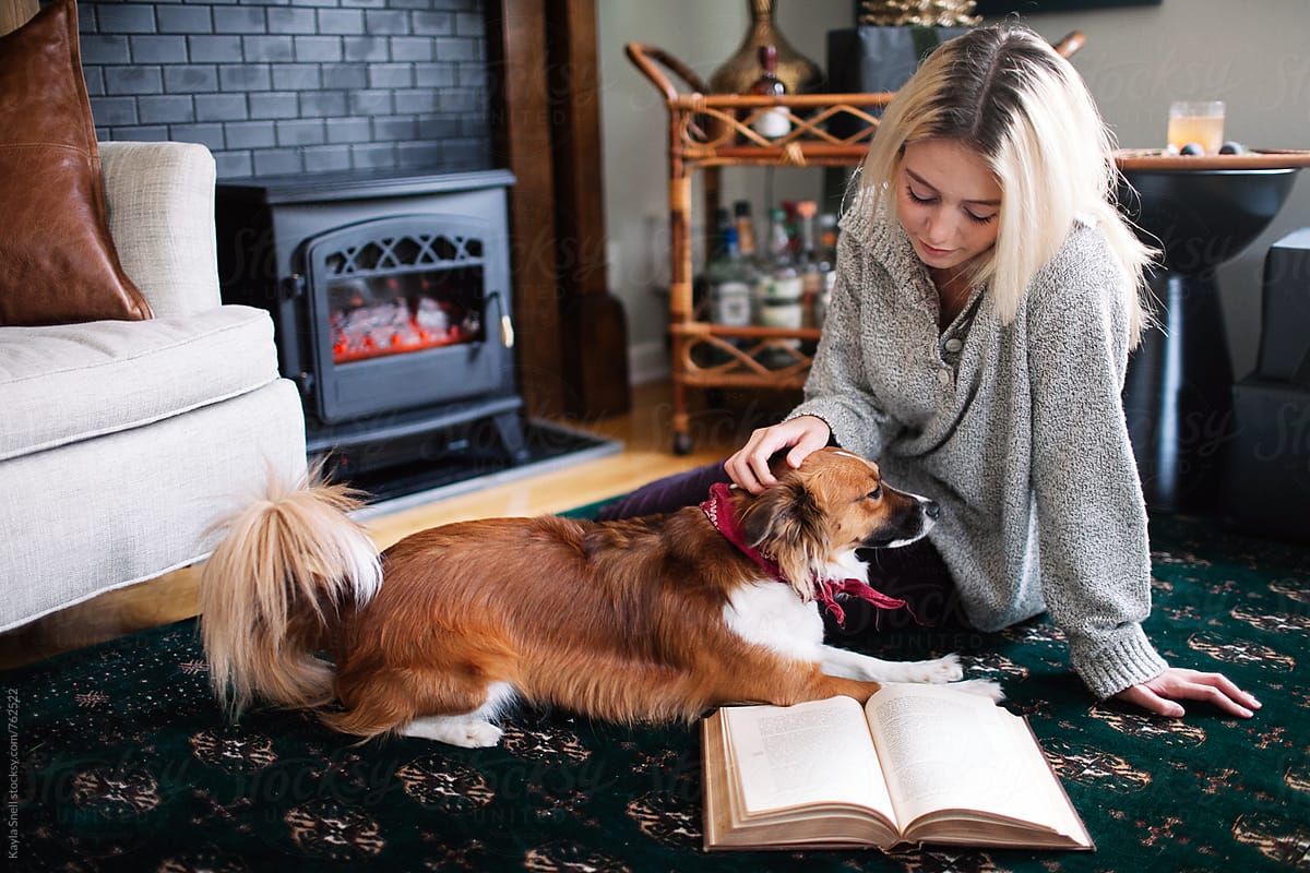 Woman playing with her dog while reading