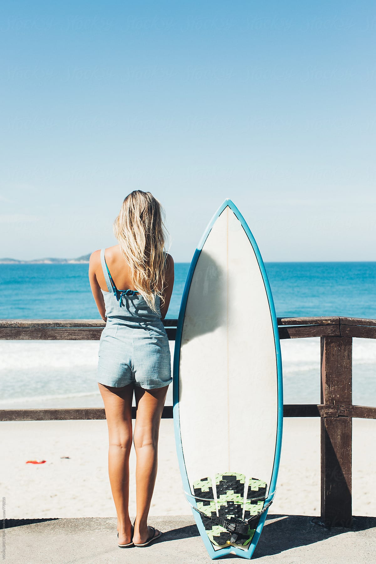 Blond Female Surfer Girl Standing Next To Surfboard On Ipanema Beach In Rio De Janeiro By