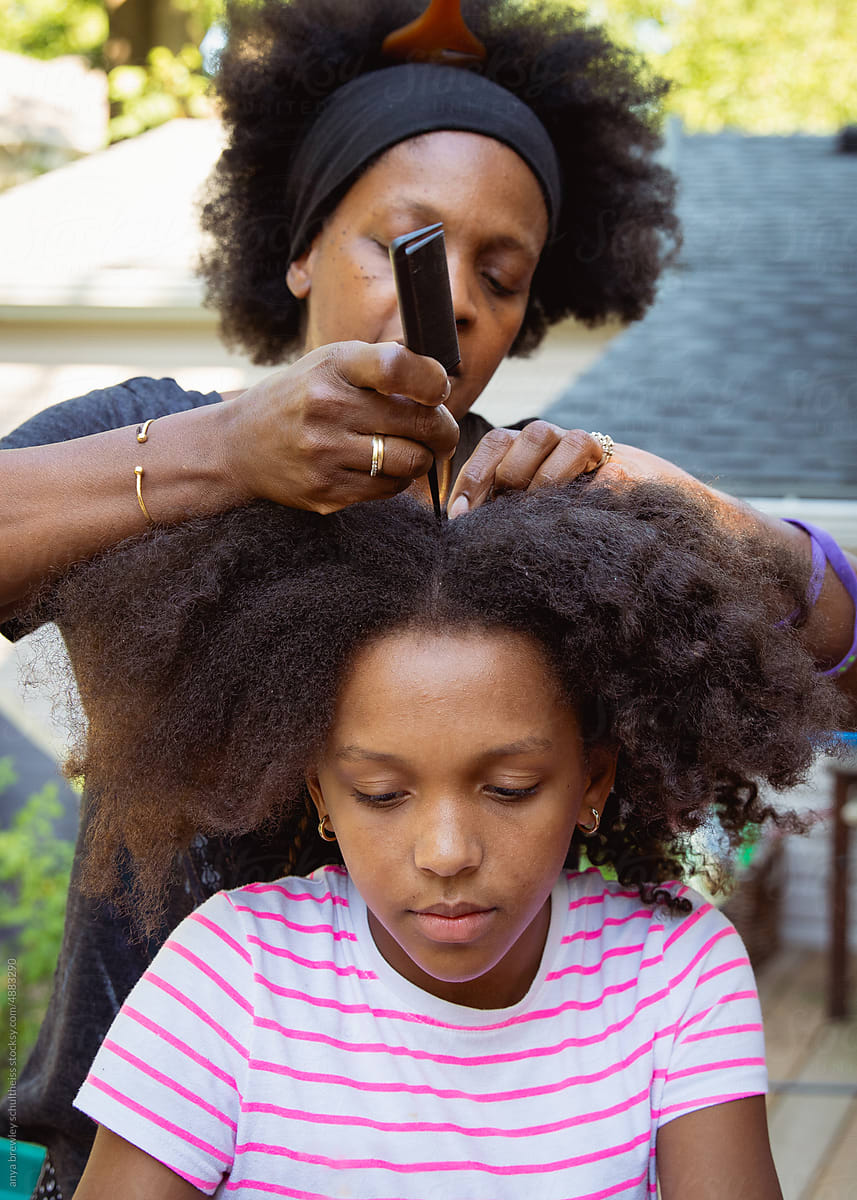 Mother combing her child\'s kinky curly coily hair
