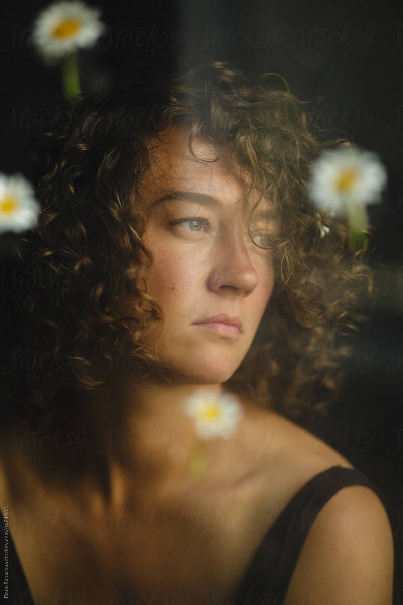 A woman with daisies is looking into the distance