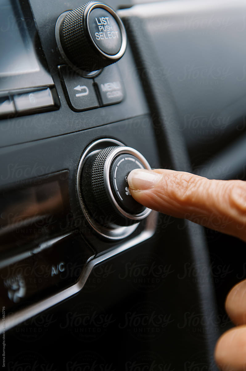 middle aged woman inside a car pushing button