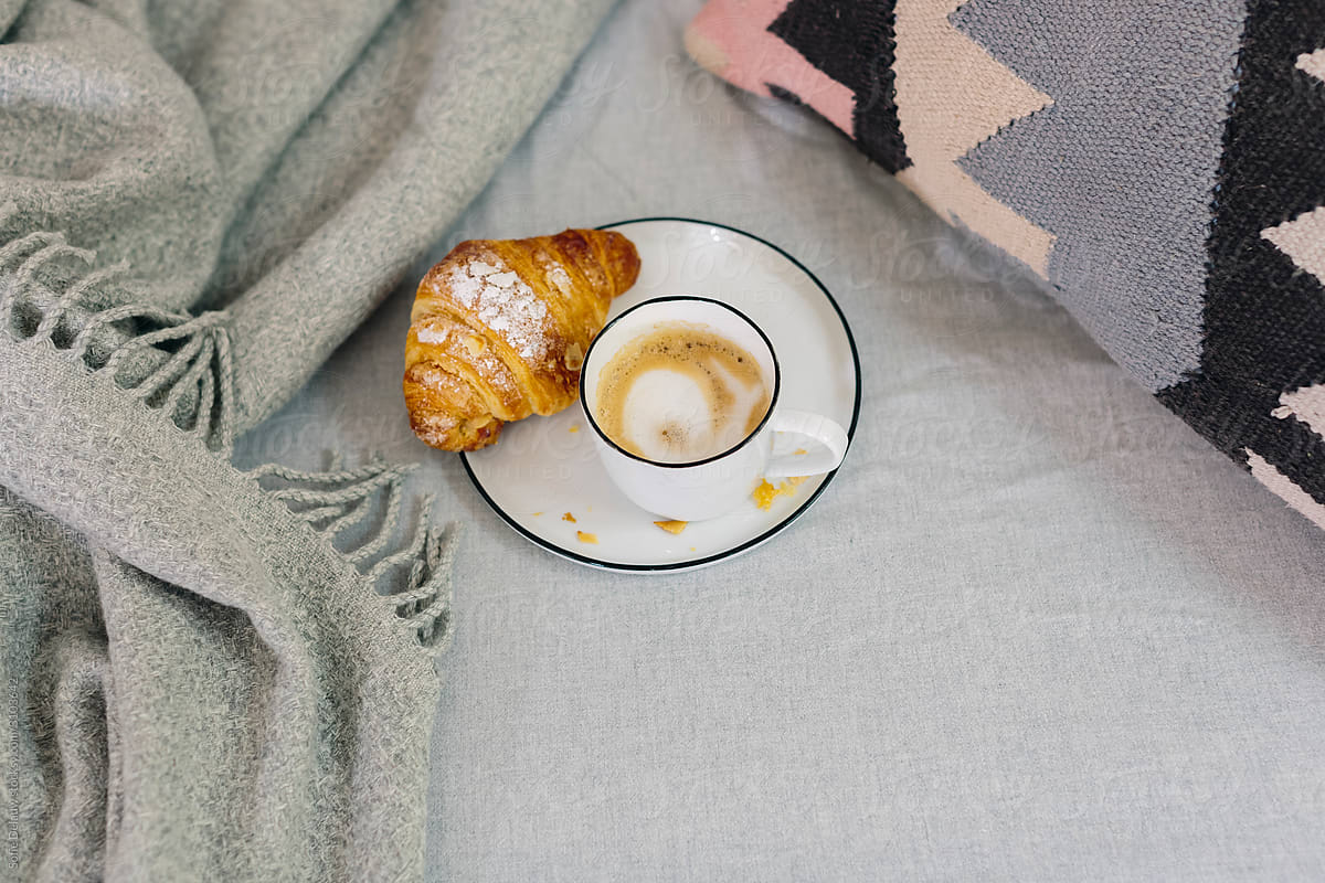 Coffee and croissant on bed in morning