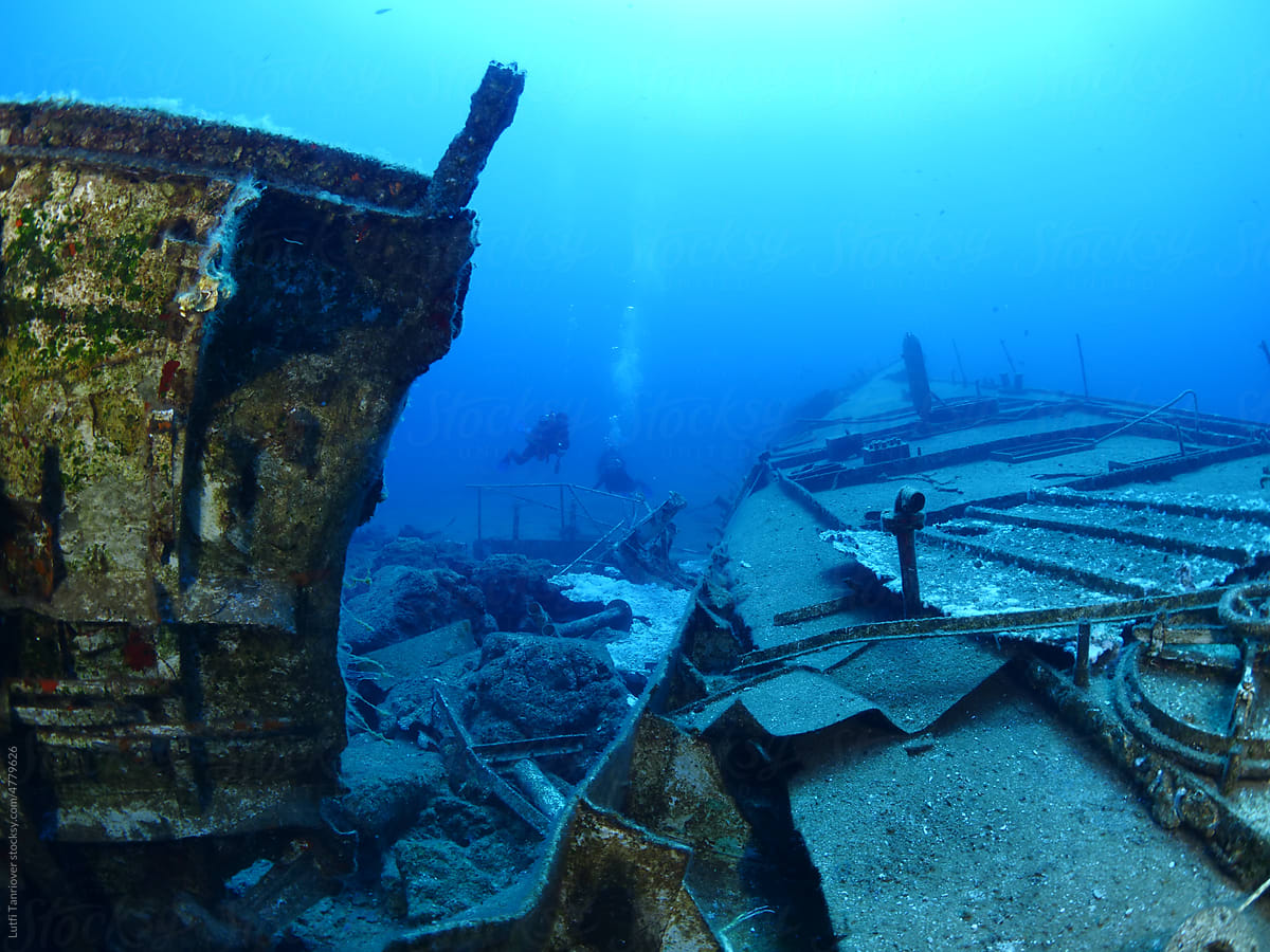 scuba divers exploring shipwreck scenery underwater ship wreck deep