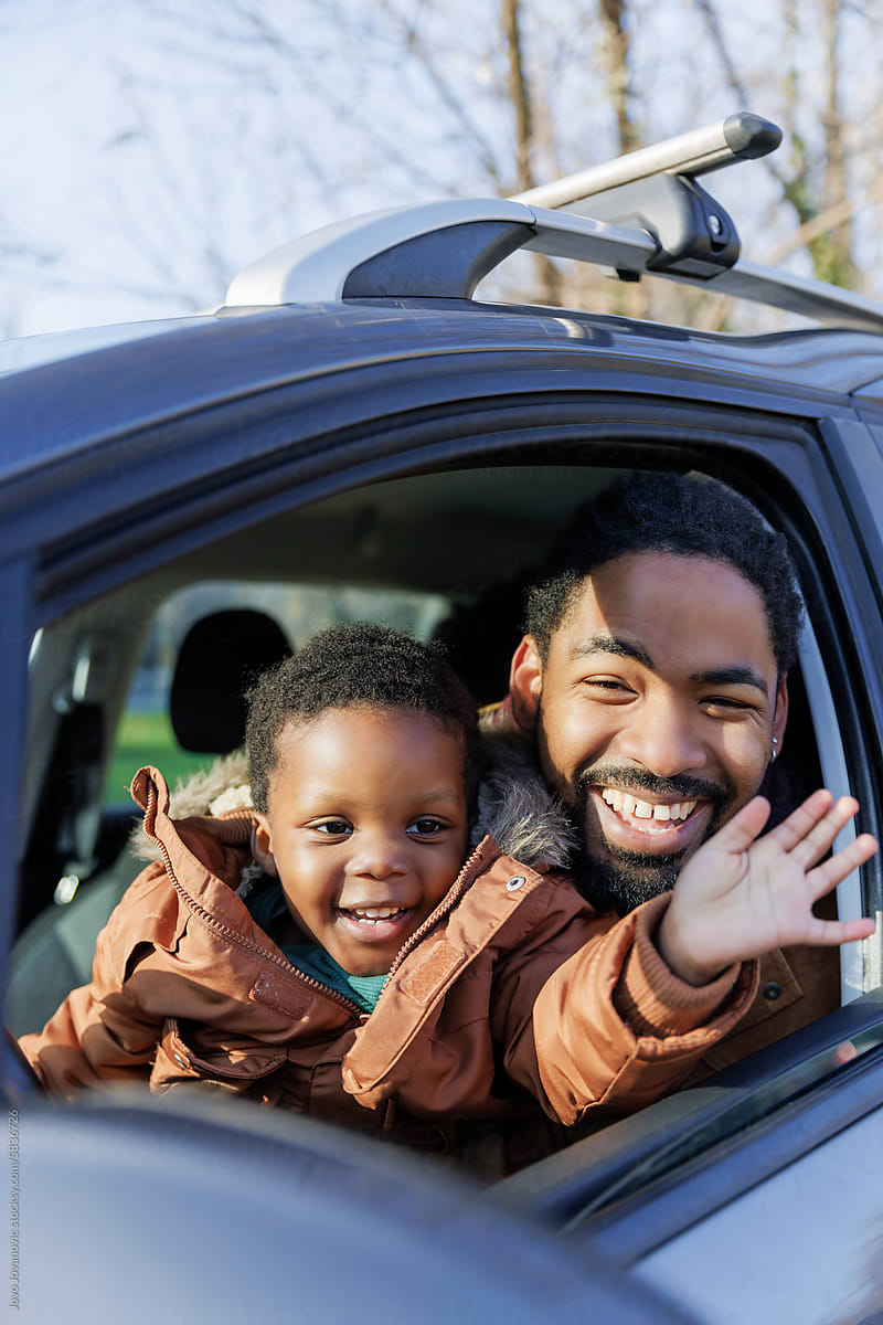 Happy kid waving while sitting with father in car