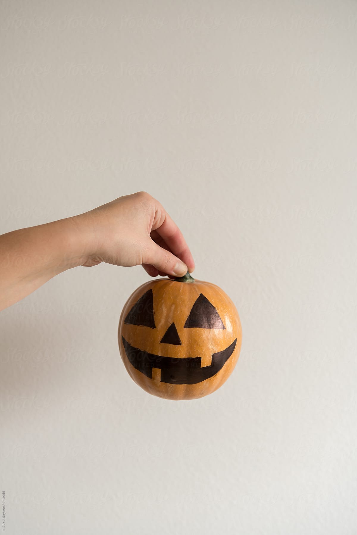 Holding a jack-o\'-lantern in hand