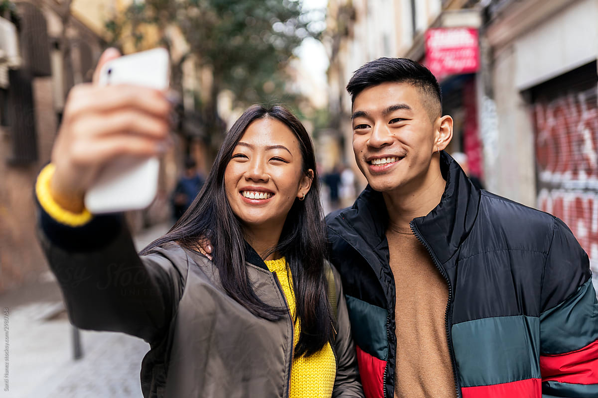 Chinese couple taking a selfie on street.