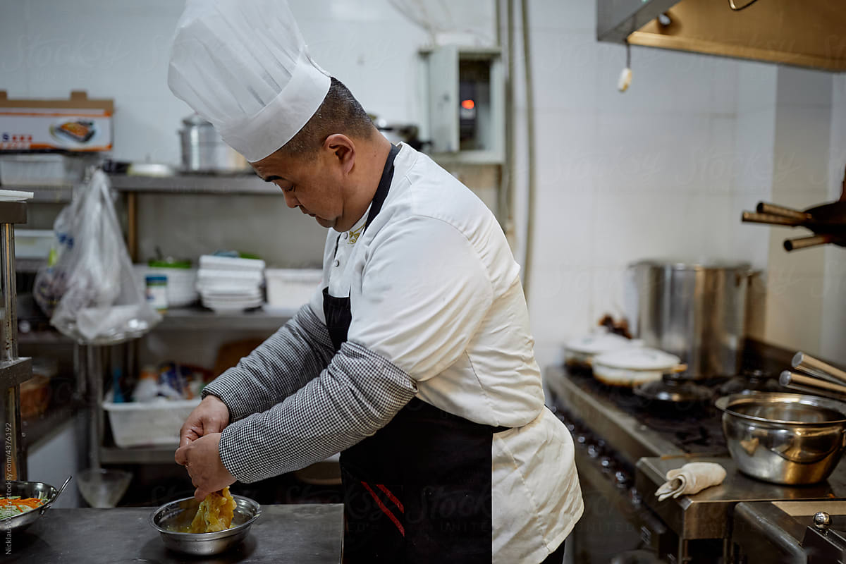 Chinese chef marinates fish in a restaurant kitchen