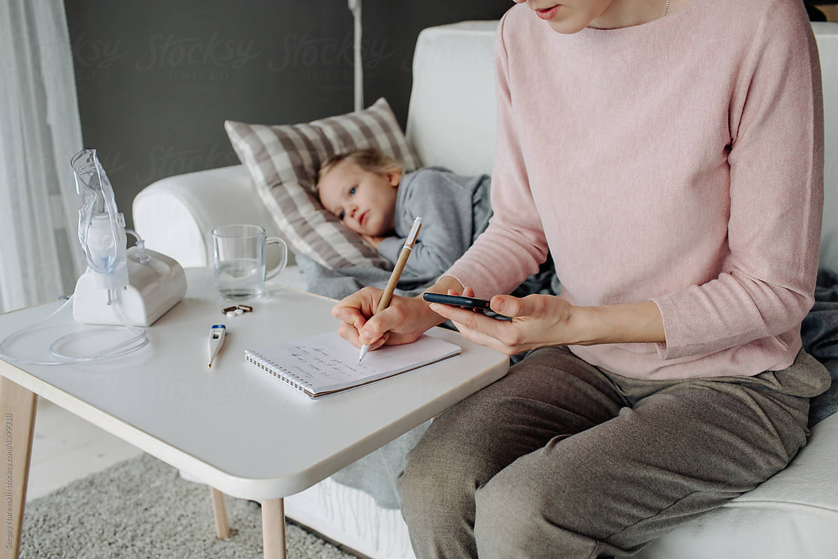 Mother with cellphone writing in notepad near sick girl