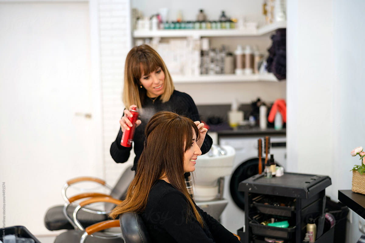 Hairdresser applying hair spray on client head