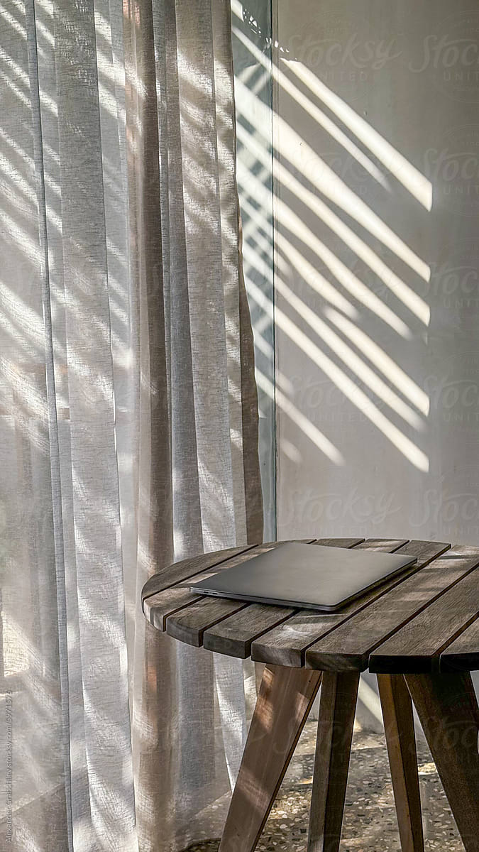 Sunlight through Sheer Curtains and Laptop On A Wooden Table