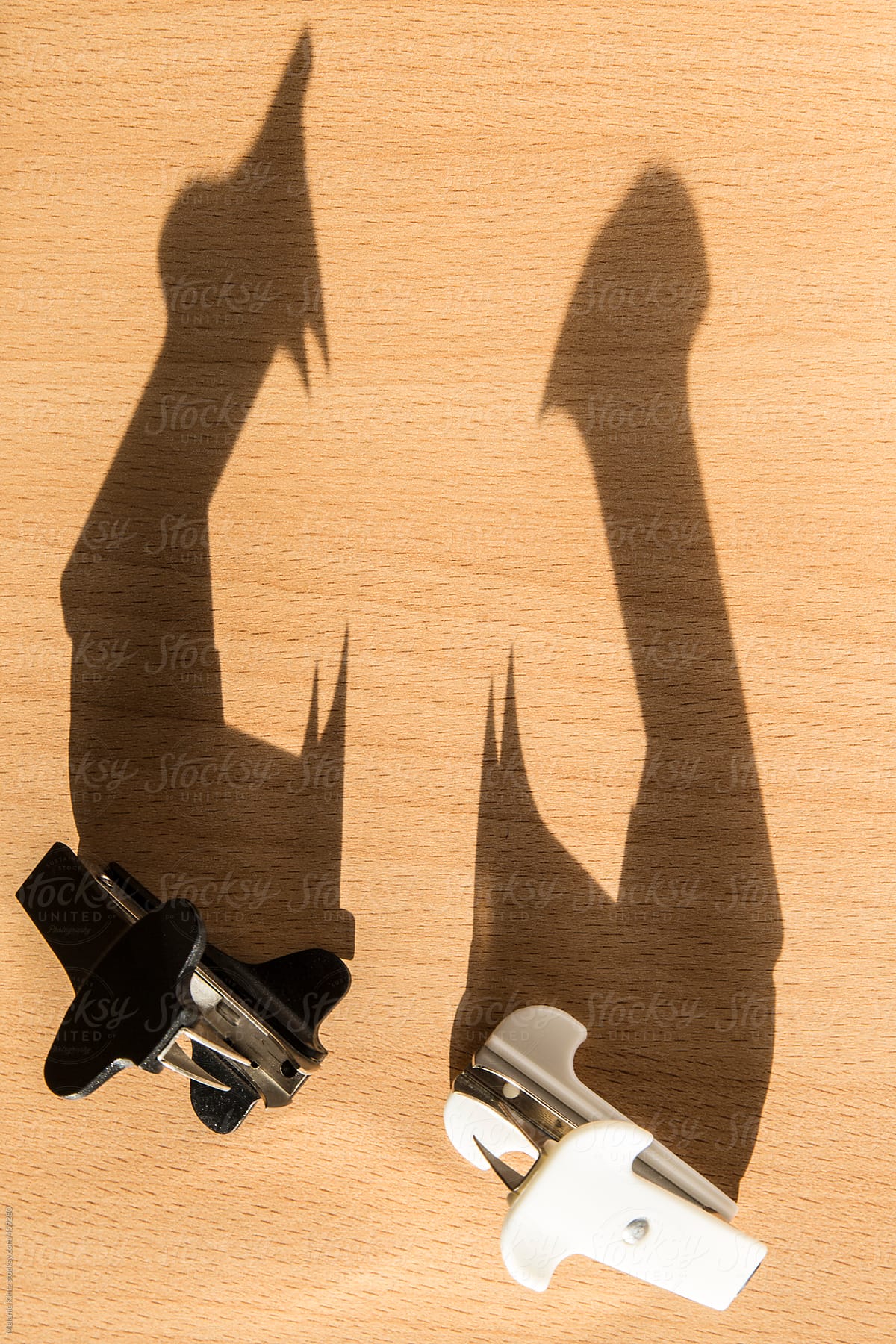 Two staple removers casting long shadows on a desk