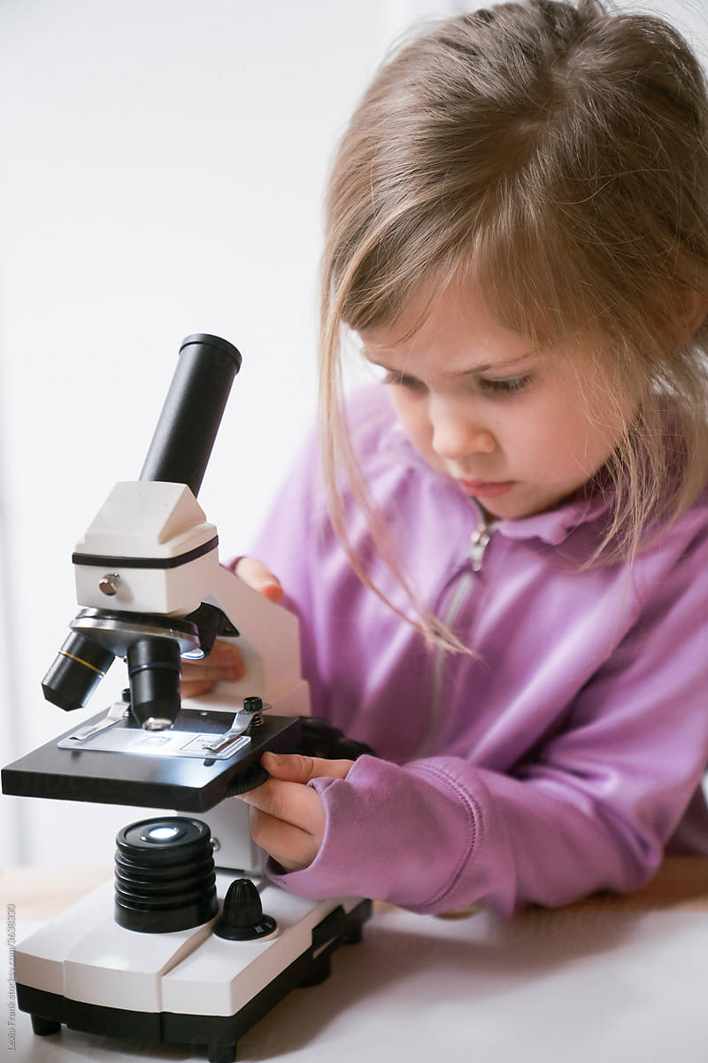 little girl uses microscope