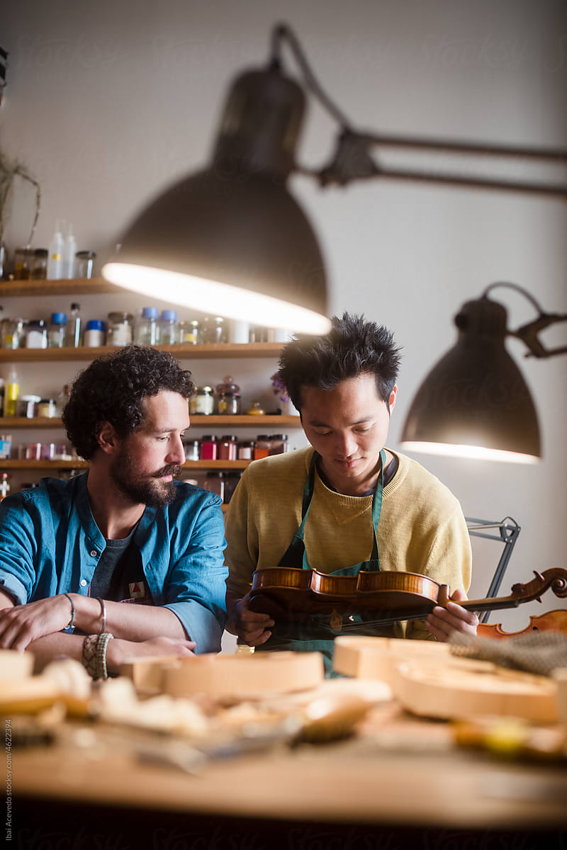 Violin luthiers examining an instrument at workshop