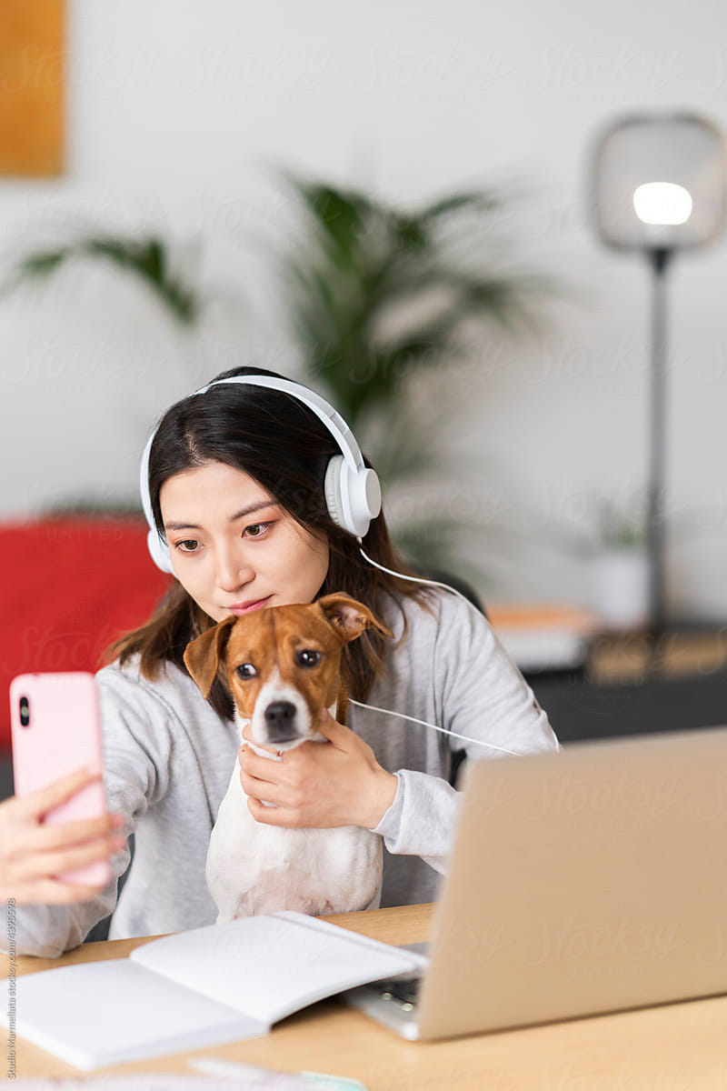 Asian lady taking selfie with dog during online studies