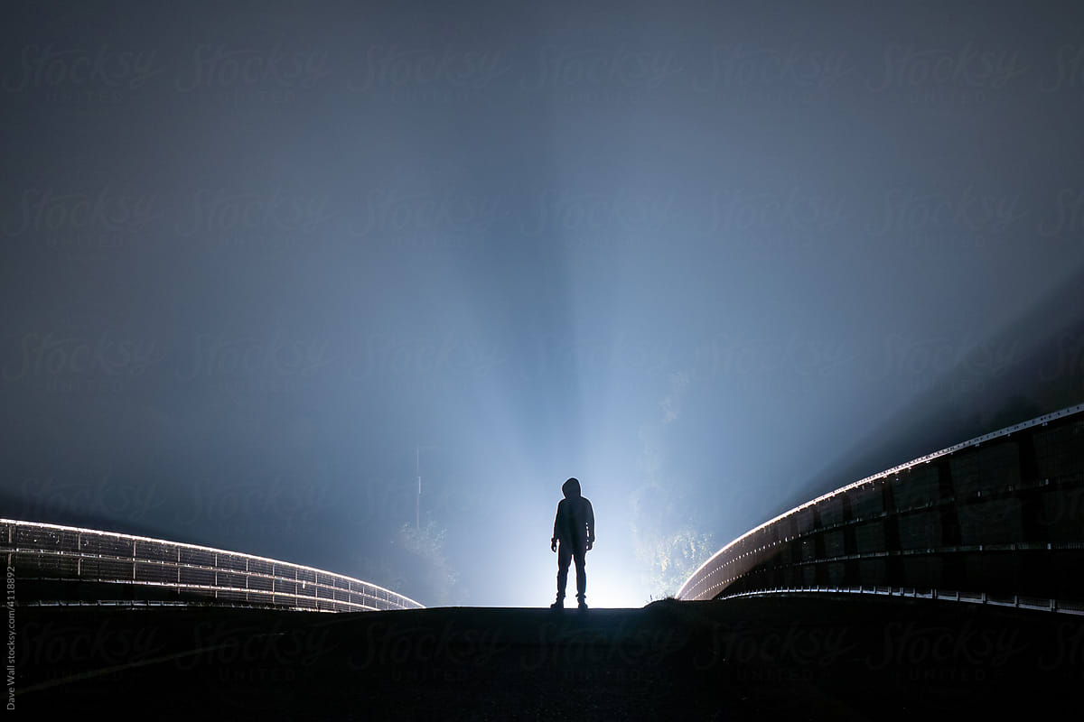 A man silhouetted on a road at night