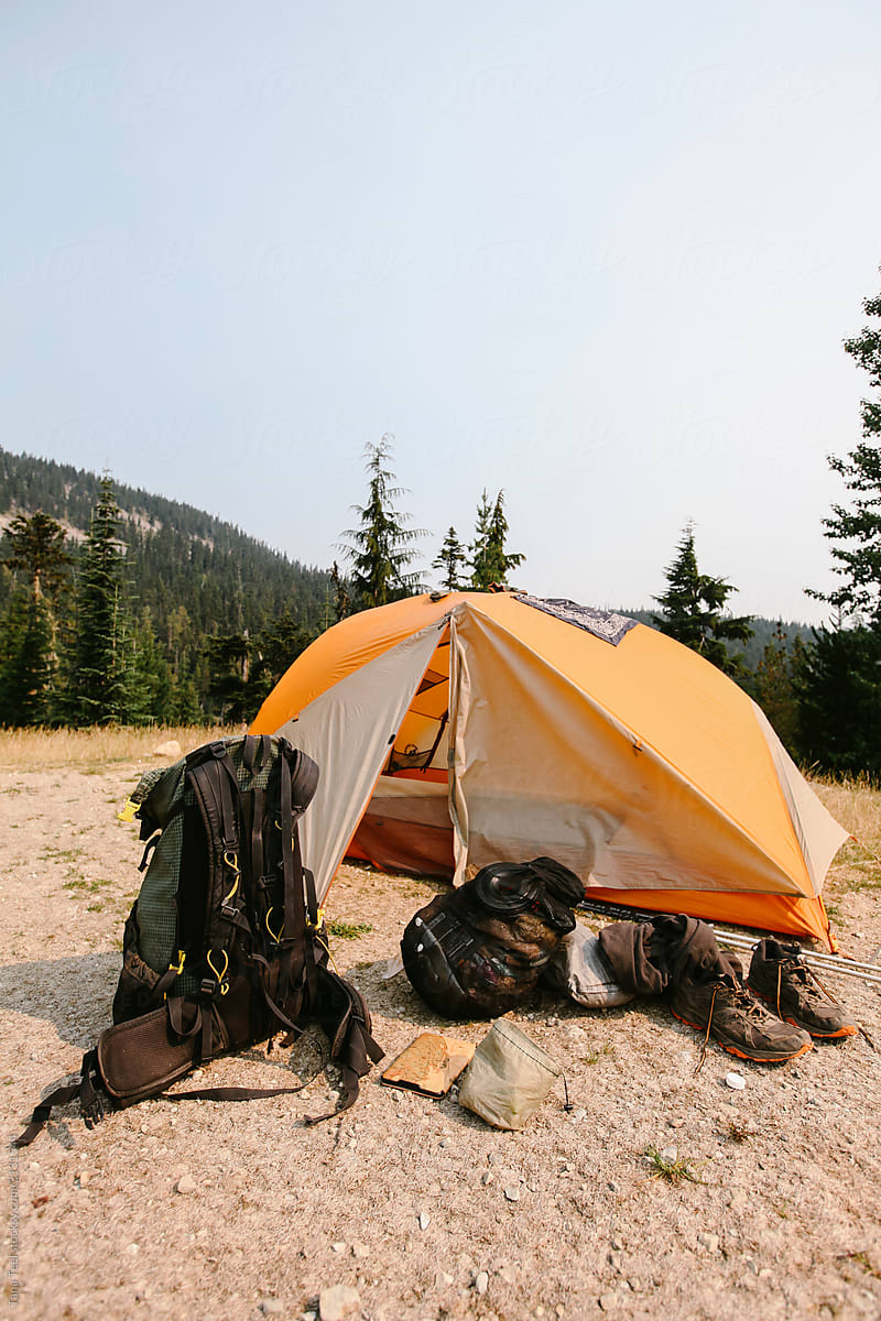 tent and camping equipment set up on forest trail