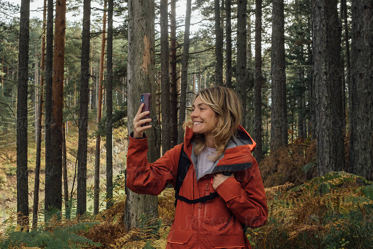 Young Woman Hiker Taking Picture With Mobile Phone in Forest