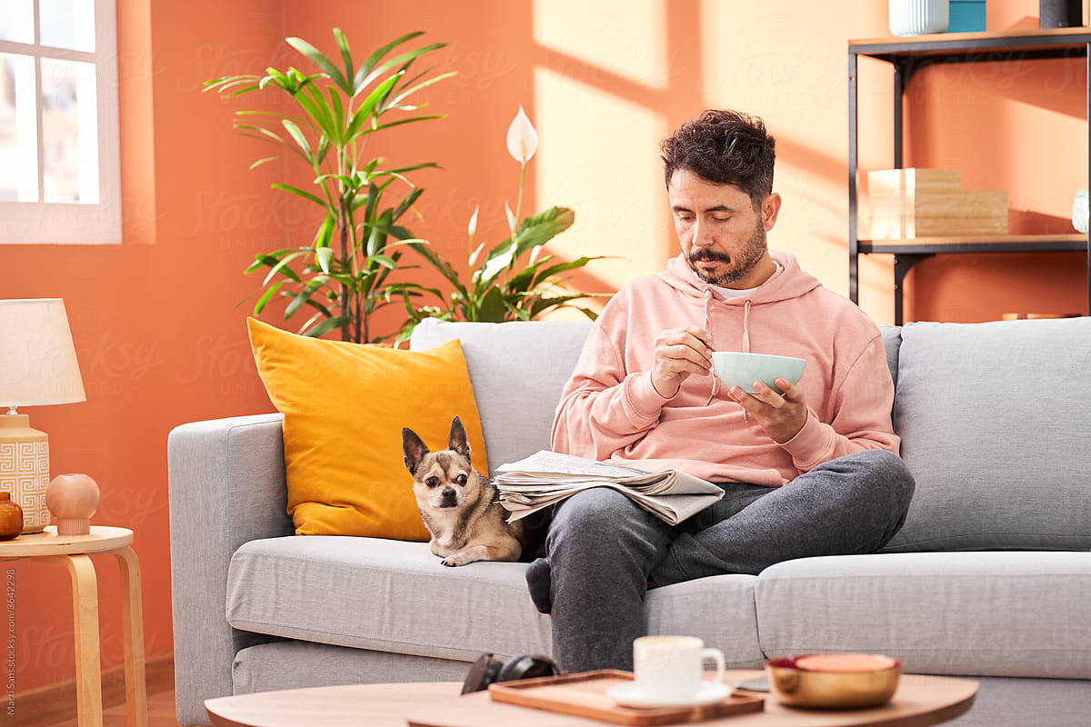 Man with newspaper having breakfast in living room with pet