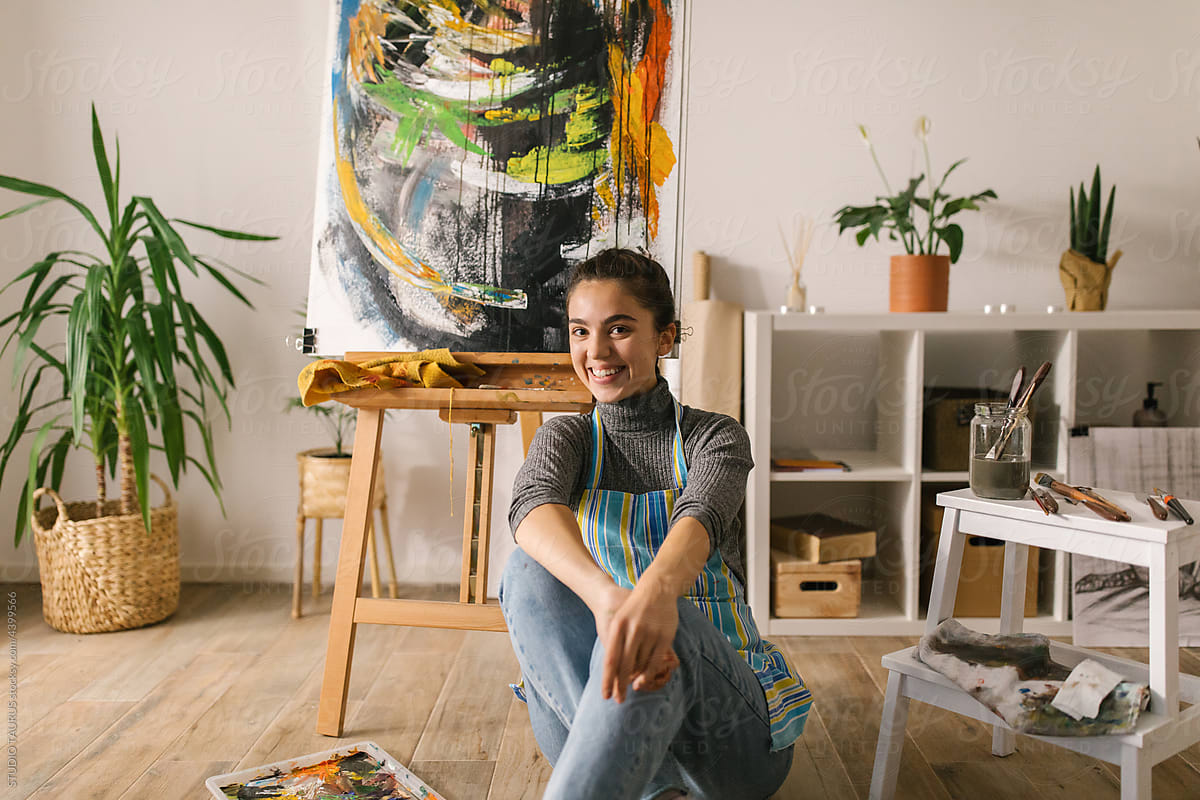 Portrait of happy artist posing with her painting