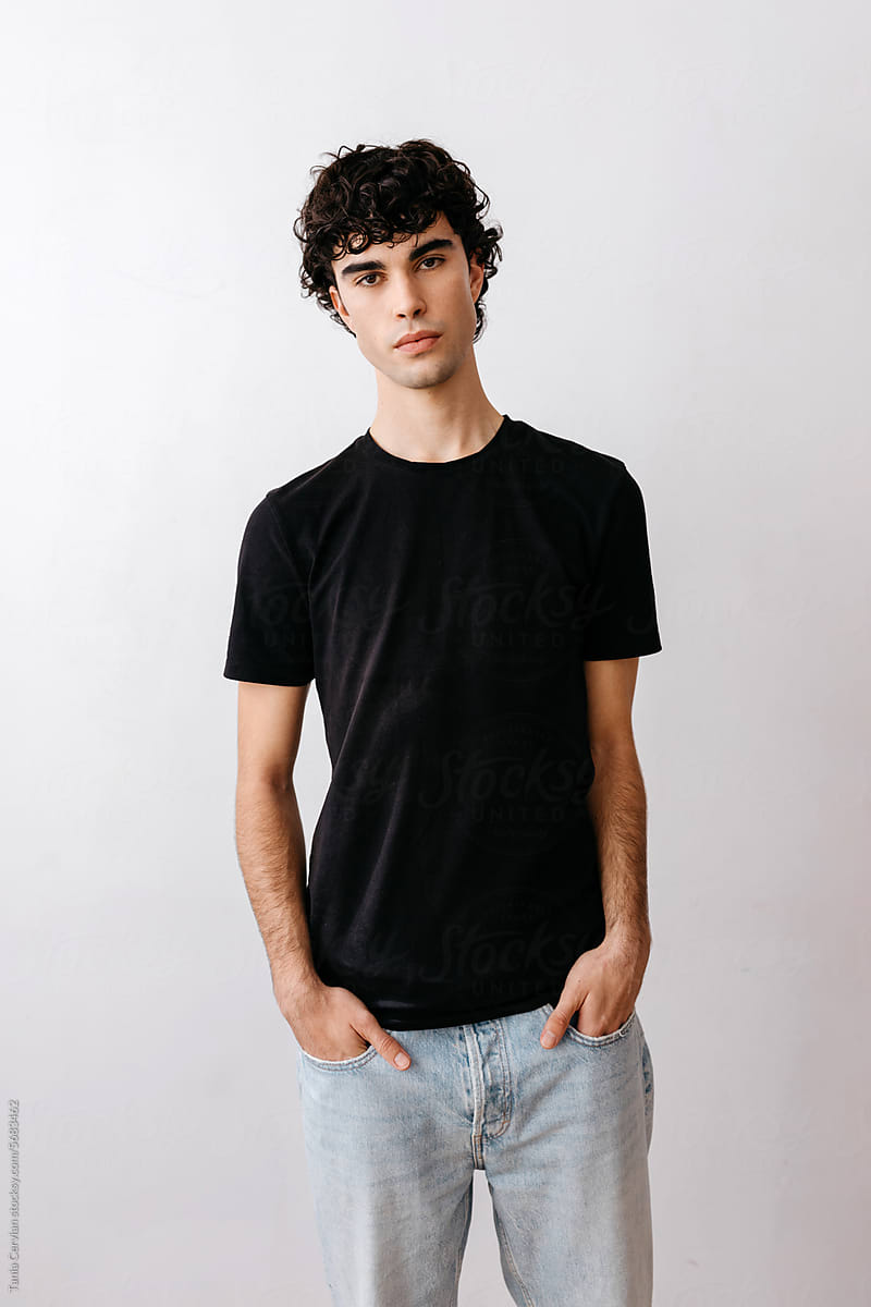 Serious young male model standing against white wall