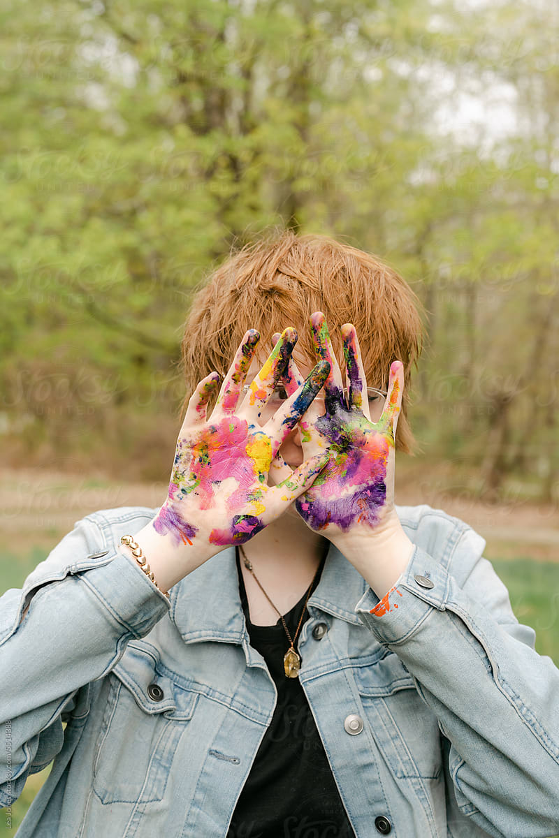 fun portrait of happy artist holding her hadn\'t covered in paint
