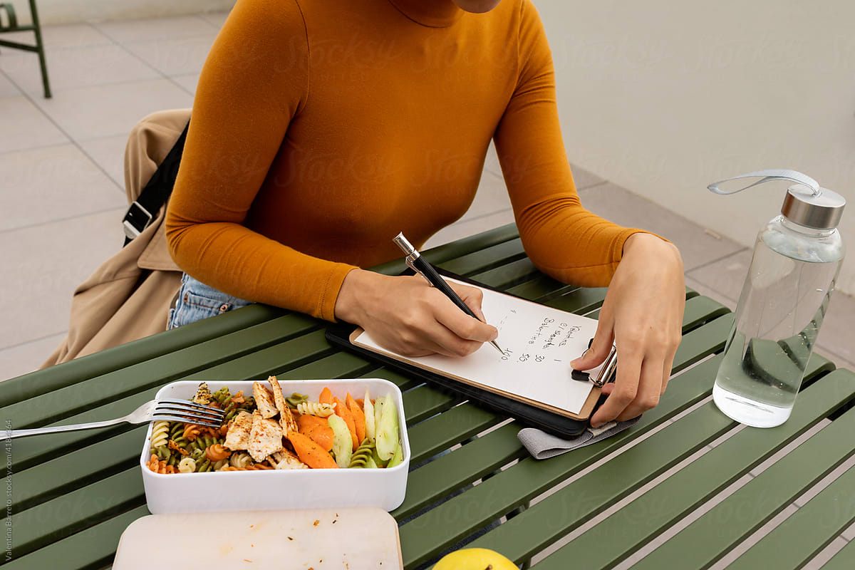 Female writing notes while having lunch