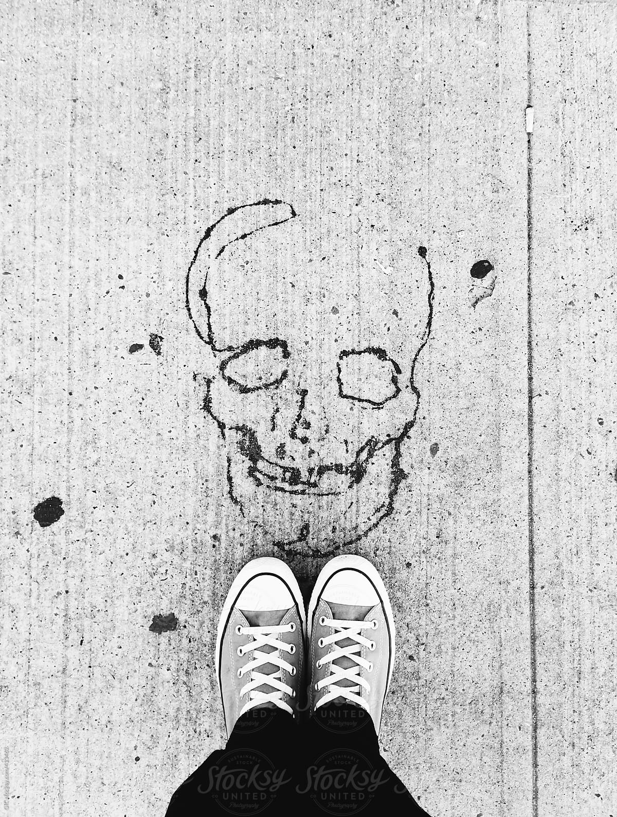 Skull printed on the asphalt and feet