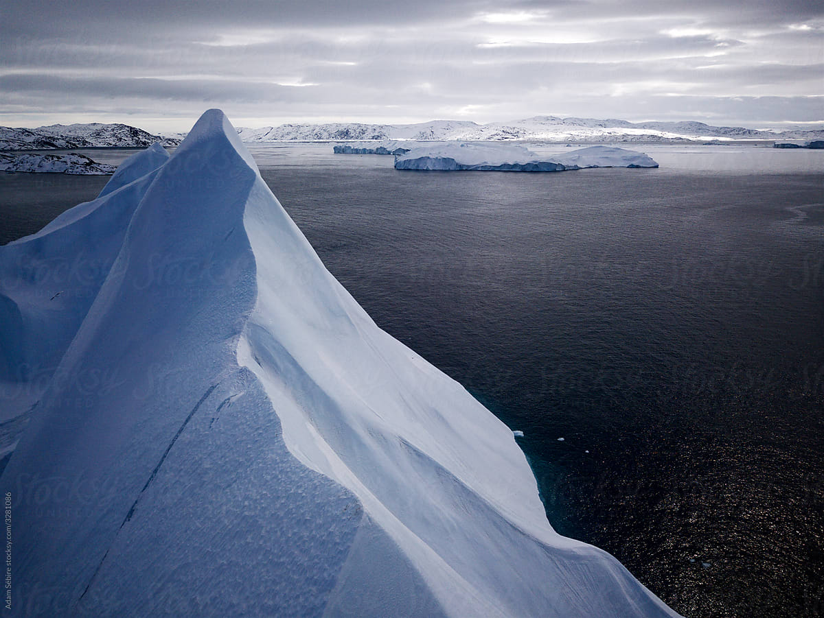 Stunning high Greenland glacier iceberg peaks melting, dramatic aerial of snowy peak