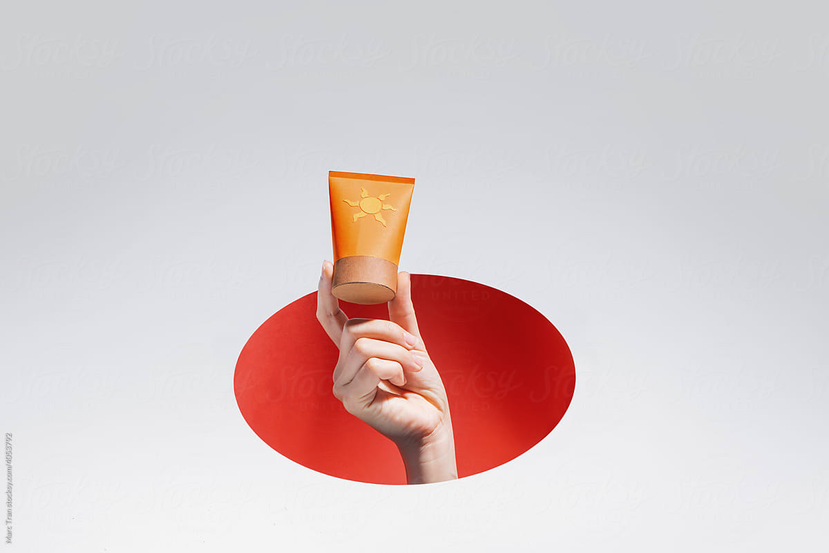 Female hands holding cosmetic bottle on orange background