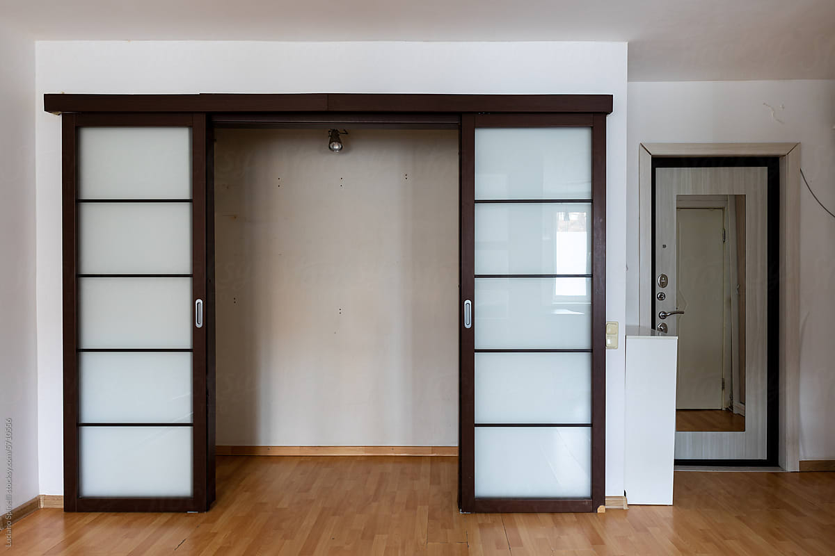 Small closet with open metal brown glass sliding doors inside studio