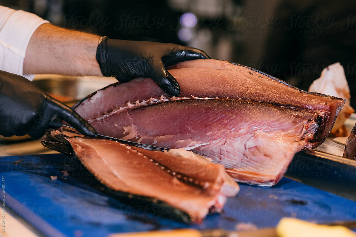 Crop person cutting raw tuna fish in restaurant