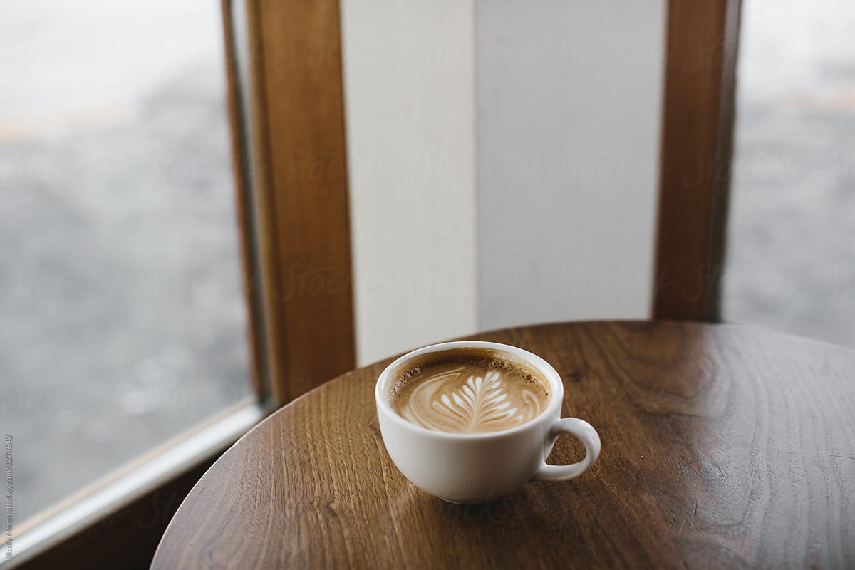 latte on dark wood table in corner of coffee shop