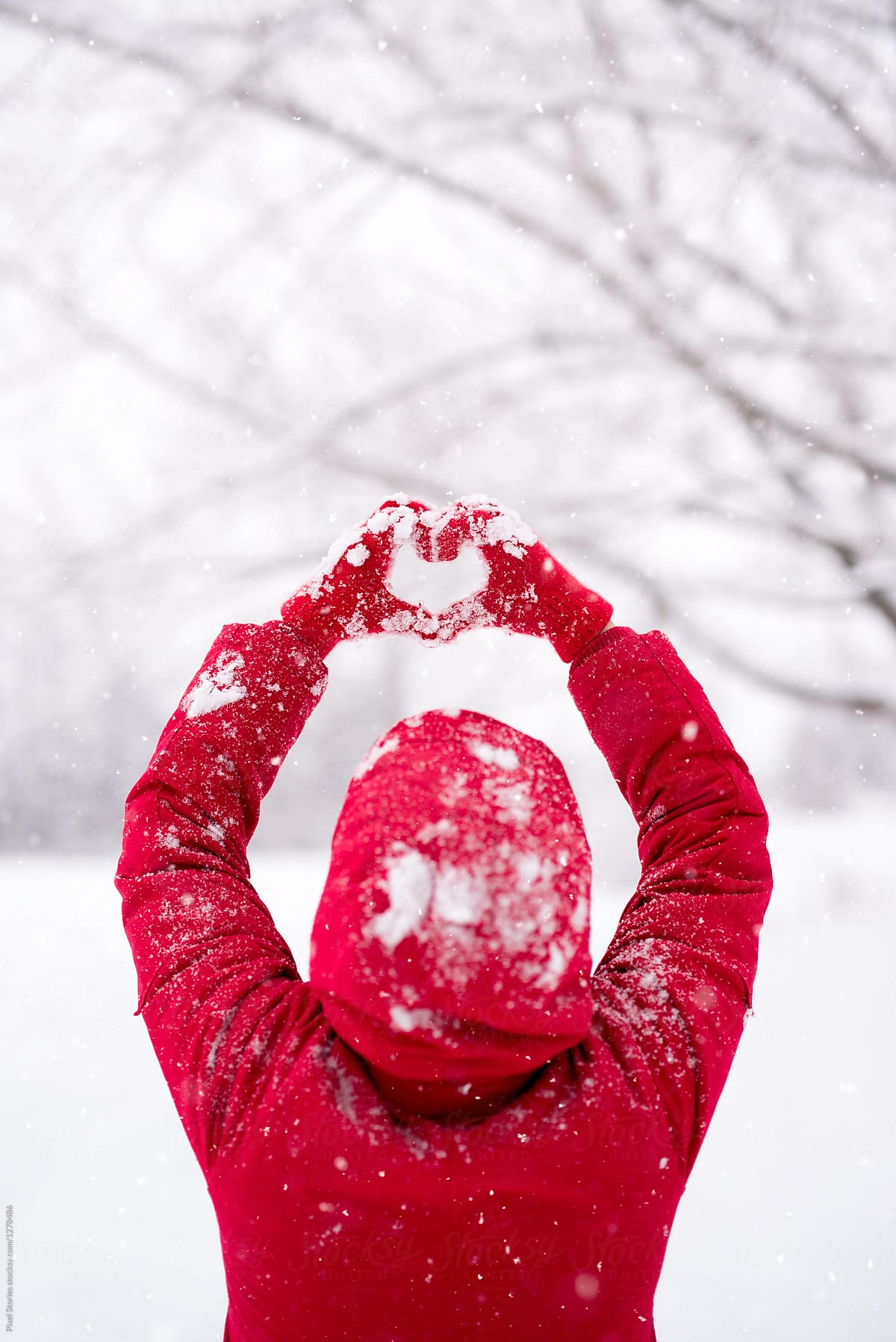 Woman making heart symbol with snowy gloves