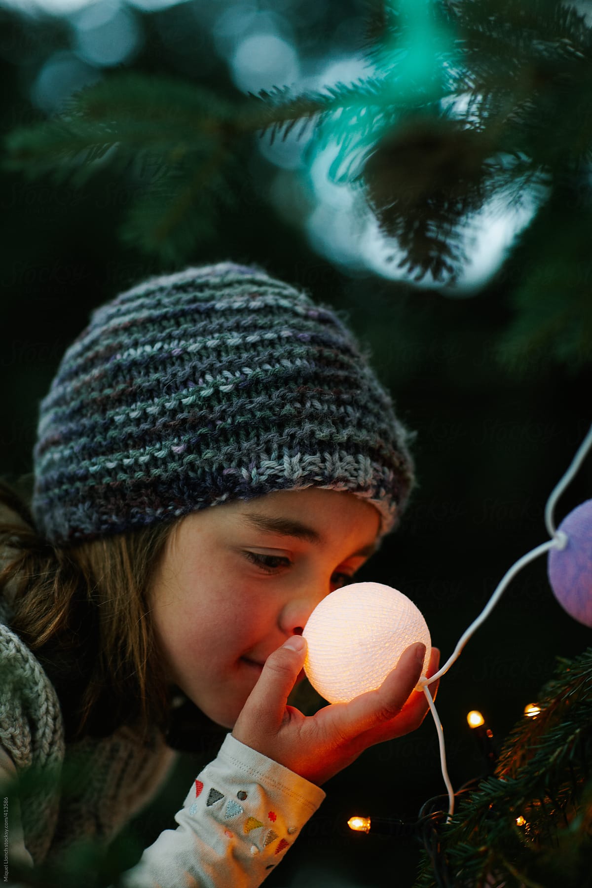 Child touching with her nose a ball at  christmas tree