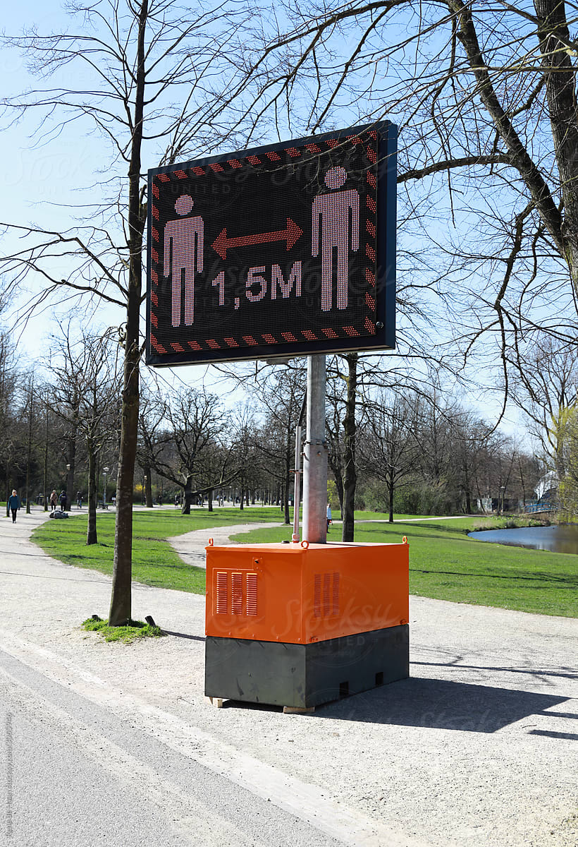 sign in park with warning to keep distance